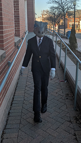 Serious dinosaur lawyer walking towards you.